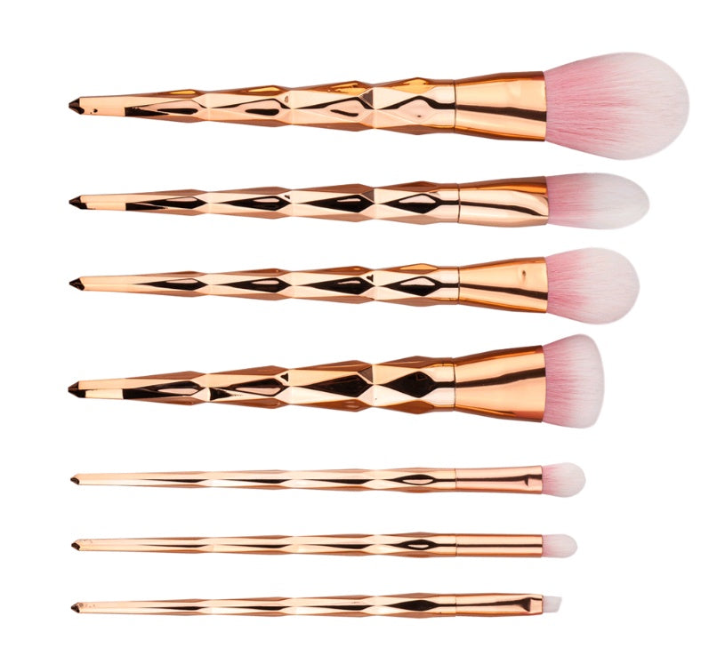 Set of rose gold makeup brushes with pink bristles on a white background